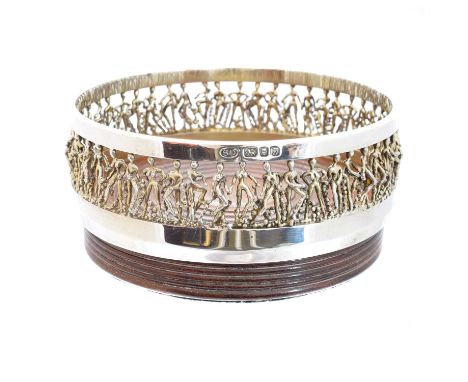 A 'cariatic' silver wine coaster by Stuart Devlin, of circular form, the turned wooden base with figural openwork sides, hall