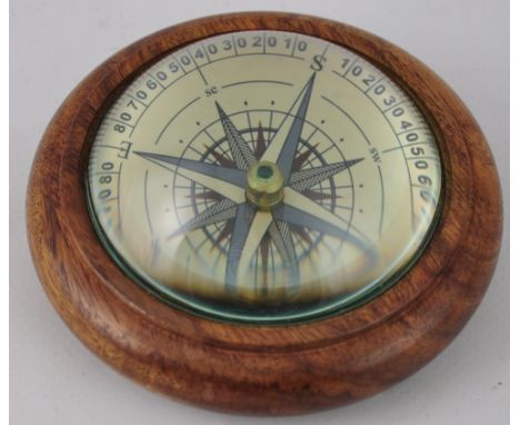 A wooden paperweight with magnified compass 