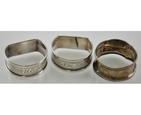 A pair of engine turned silver knapkin rings together with one other