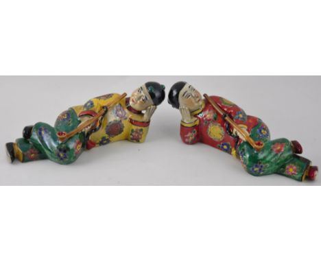 A pair of porcelain figures modelled as reclining opium smokers