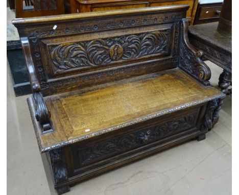 An early 20th century carved & panelled oak bench, with rising seat & lion mask decoration, length 4' 1", height 3'