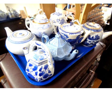 A tray containing seven antique and later ceramic teapots and lidded sugar basins