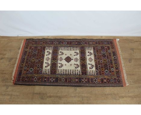 Eastern rug with geometric decoration and central panel depicting animals on red, blue and cream ground, 169cm x 88cm