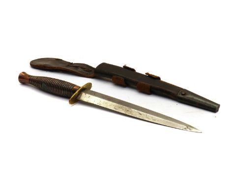 A Fairbairn Sykes style fighting knife,mid-20th century, with a bronzed grip and brass guard, within a leather,blade 17cm lon