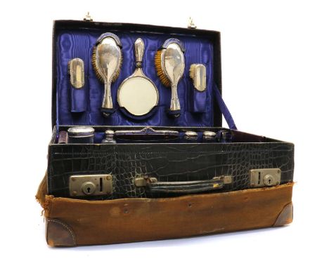 An Edwardian crocodile skin suitcase with a silver vanity set,by William Devenport, Birmingham 1909-1910, comprising a handhe