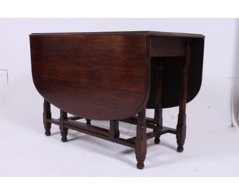 A 20th century oak drop leaf dining table raised on gun barrel supports, the leaves raising on gate leg supports. Measures: 7