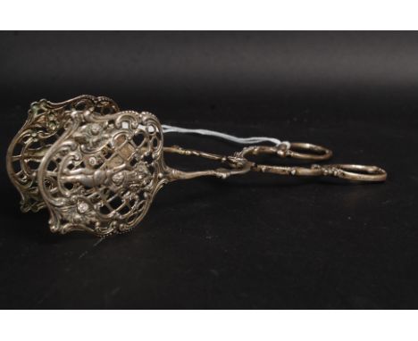 A white metal ( marked ' 800 ' indicating silver ) pair of ice / sugar tongs, heavily detailed allover. 