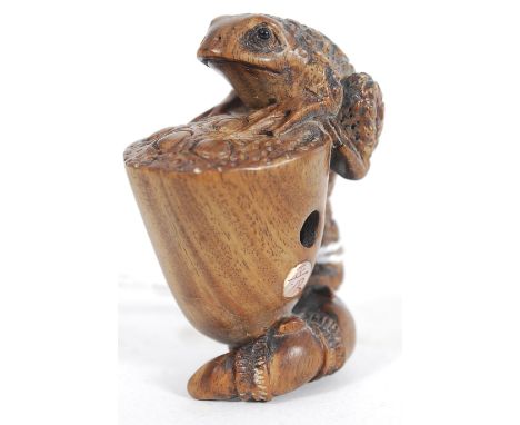 A Japanese oriental carved wood netsuke of a frog and dish