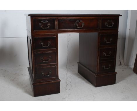 A Georgian style mahogany kneehole pedestal desk raised on bracket feet with a series of drawers to the pedestals and desk to