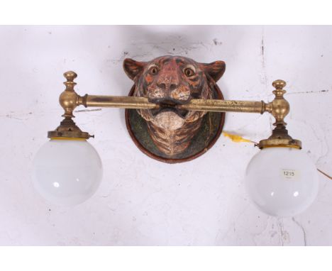 A fabulous 20th century twin tiger mask wall light. The large head of decorative form having brass pole to mouth with twin mi