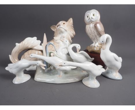 A Lladro model Papillion dog, 8” high, a model owl, 6 1/4” high, and four model swans