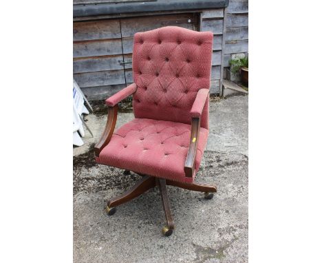 A desk elbow chair, button upholstered in a red fabric, on swivel splay castored support
