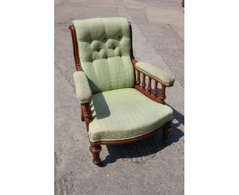 An Edwardian oak showframe armchair, button upholstered in a green patterned fabric, on reeded and castored supports