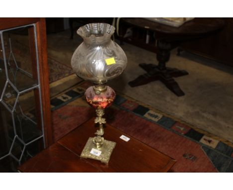 An early 20th century brass and cranberry glass oil lamp 
