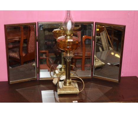 A modern brass and amber glass table lamp in the style of a 19th century oil lamp 