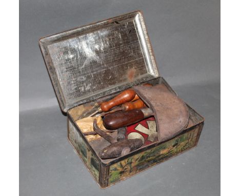 An old biscuit tin containing various leather working tools 