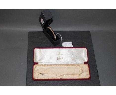 A yellow metal textured bangle marked 9 ct bonded gold and a simulated pearl necklace, cased