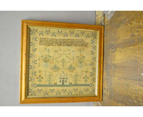 An early 19th century polychrome needlework sampler, decorated with a cottage surrounded by stylised plants and trees, bears 