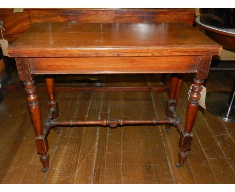 A late Victorian walnut card table, the hinged top enclosing a baize lined interior, raised on ring-turned tapered legs and c