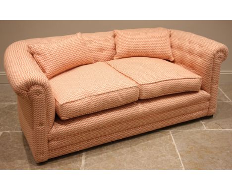 A Chesterfield sofa, later re-covered in chevron banded fabric, of typical deep seated form with a button back and scrolled p