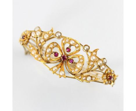 A Victorian style untested ruby and pearl bangle, the central bow shaped motif set with four graduated untested rubies with f