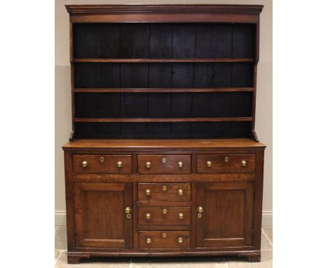 A late George III Welsh oak dresser, the plate rack with a moulded cornice and plain frieze over three enclosed shelves, upon