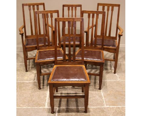 A set of six golden oak Arts and Crafts style dining chairs, early 20th century, each with an angular lath back over a padded