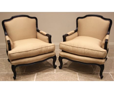 A pair of French fauteuil type armchairs, late 20th/early 21st century, in gold coloured lattice pattern fabric, the ebonised