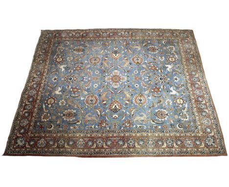 A Persian Tabriz wool carpet, with an all-over traditional foliate and zoomorphic design against a blue ground, circumscribed