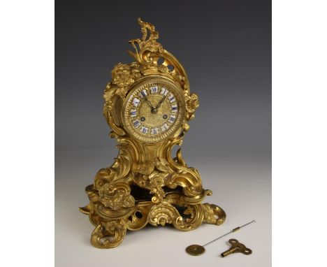 A Rococo revival gilt metal eight day mantel clock, late 19th century, the case of cast scrolled acanthus form applied with a