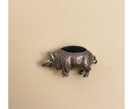 A novelty silver pin cushion in the form of a pig, with blue velvet back, and engraved decoration. 