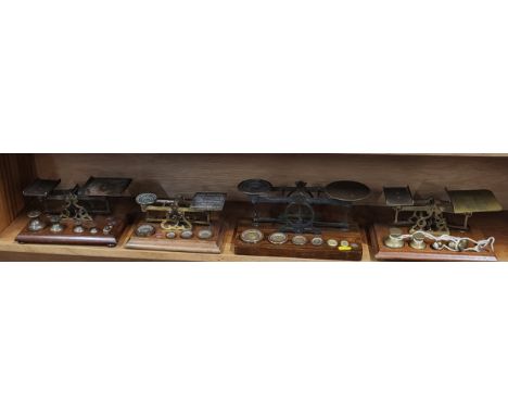 A set of four vintage weighing scales, with brass weights, on wooden base.