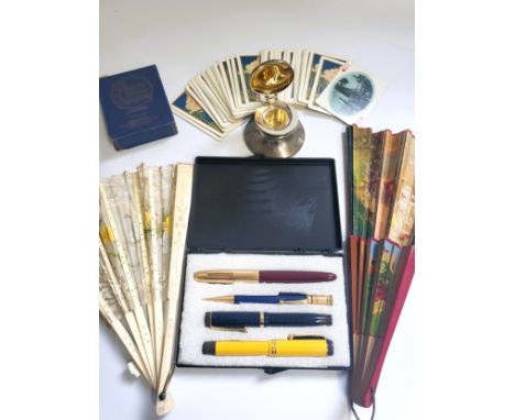 A collection of three fountain pens, a propelling pencil, a silver inkwell, a pair of antique playing cards and two ladies fa