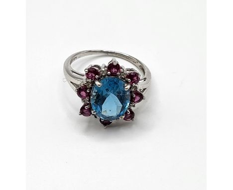 A 9ct white gold, blue topaz, and ruby cluster ring, with small diamond accents, size R.4.1 grams