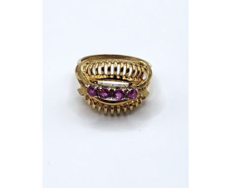 A yellow metal and ruby cocktail ring, set with four round-cut rubies, in openwork ribbed mount, size P.6.5 grams