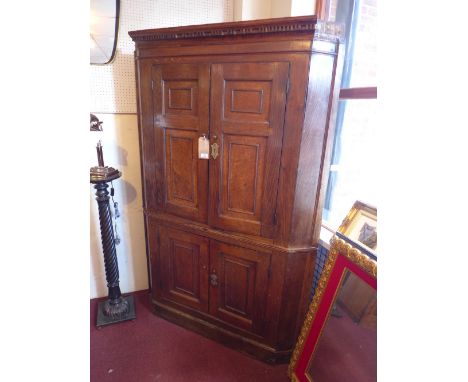 A late 18th/early 19th Century large oak corner cupboard with four doors enclosing shelf space. 