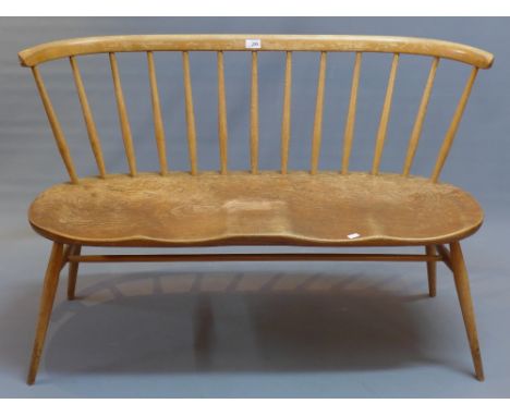 An Ercol elm two seater bench raised on tapered legs jointed by stretcher