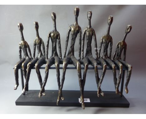 After Giacometti a figural sculpture of people sitting on a bench. 