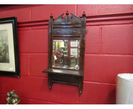A lacquered rosewood effect wall mirror with shelf, 72cm x 32.5cm