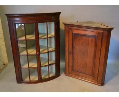 A George III oak hanging corner cabinet, together with a 19th century bow fronted hanging corner cabinet 