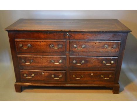 A George III oak mule chest, the hinged plank top above six drawers with brass handles raised upon bracket feet, 134cms wide,