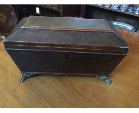 A Regency thuya wood tea caddy
Of sarcophagus shape, with hinged rectangular lid, enclosing two canisters, with rings handles