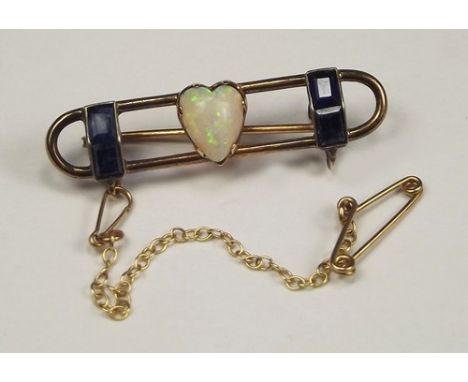 OPAL BROOCH.
A yellow metal brooch, set a heart shaped opal, 8 x 7mm max. & flanked by pairs of baguette cut sapphires. Lengt