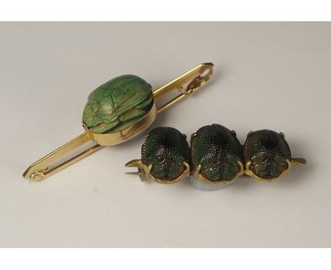 SCARAB BROOCHES.
A yellow metal brooch, set an ancient green ceramic scarab & a triple scarab beetle bar brooch.