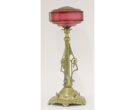 A brass oil lamp base,in the style of Dr Christopher Dresser, with a facet cut cranberry reservoir and a loaded base,41.5cm