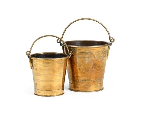 A GRADUATED NEAR PAIR OF COLONIAL BRASS BUCKETS  18TH OR 19TH CENTURY  Swing handles above ring incised tapering bodies, one 