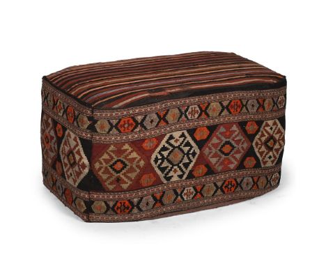 A KILIM UPHOLSTERED OTTOMAN OR FOOTSTOOL THE KILIM LATE 19TH OR EARLY 2OTH CENTURY 49cm high, 92cm wide, 62cm deep