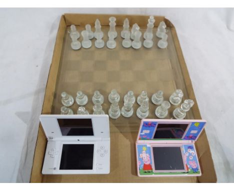 Two Nintendo DS hand held consoles and a glass chess set