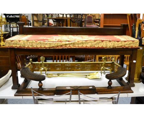 An early 20th century mahogany window seat, a carved oak club fender, a brass fender, andirons and fire tools 