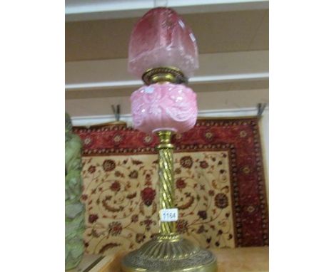 A Victorian brass oil lamp with cranberry glass shade